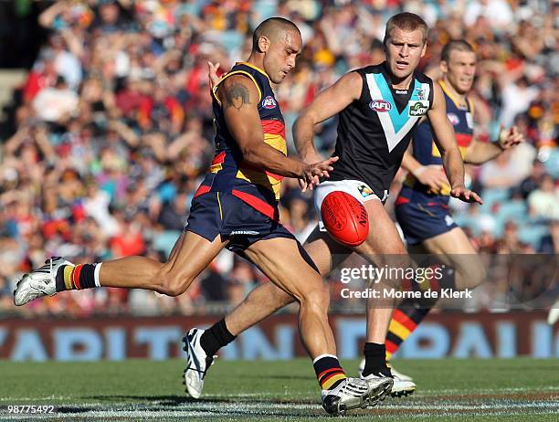 Andrew McLeod of the Crows kicks in front of Kane Cornes of the Power during the round six AFL match between the Adelaide Crows and the Port Adelaide...