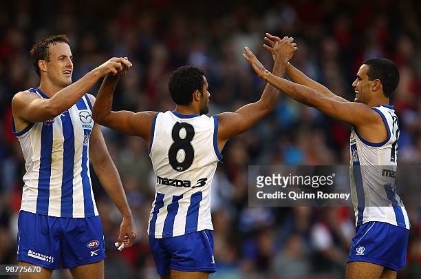 Daniel Wells of the Kangaroos is congratulated by David Hale and Lindsay Thomas after kicking a goal during the round six AFL match between the North...