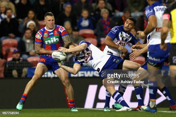 Shaun Kenny-Dowall of the Knights contests the ball against Jeremy Marshall-King of the Bulldogs during the round 16 NRL match between the Newcastle...