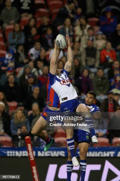 Shaun Kenny-Dowall of the Knights contests the ball against Jeremy Marshall-King of the Bulldogs during the round 16 NRL match between the Newcastle...