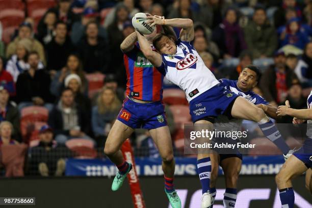 Shaun Kenny-Dowall of the Knights contests the ball against Jeremy Marshall-King of the Bulldogs during the round 16 NRL match between the Newcastle...