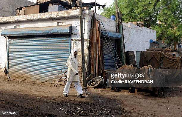 An Indian pedestrian walks past a scrap metal dealers shop in Mayapuri market in New Delhi on May 1 where one person was killed and four were injured...