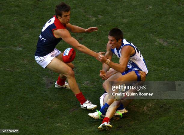 Ryan Bastinac of the Kangaroos handballs whilst being tackled by Jack Trengove of the Demons during the round six AFL match between the North...