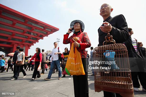 Shanghai resident holds a birdcage with the mascot of Shanghai Expo Haibao in front of China Pavilion on the opening day of the Shanghai World Expo...
