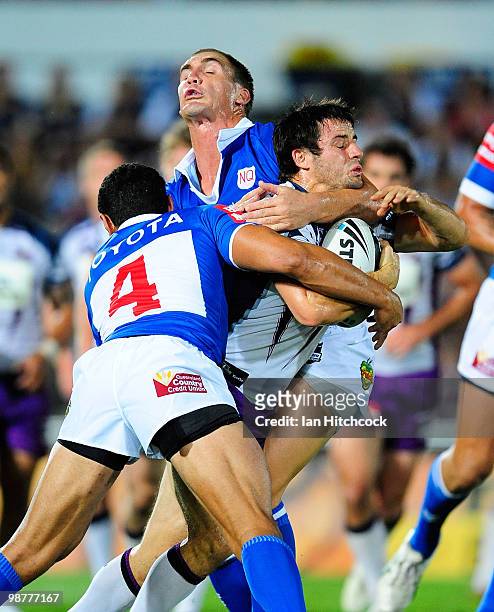 Cooper Cronk of the Storm is ackled by Scott Bolton and Willie Tonga of the Cowboys during the round eight NRL match between the North Queensland...