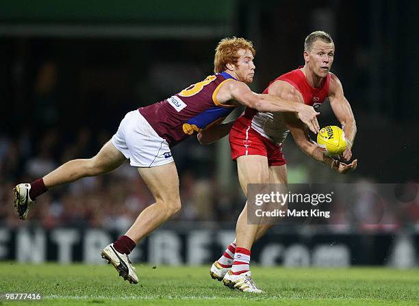 Ryan O'Keefe of the Swans handballs under pressure from Matt Austin of the Lions during the round six AFL match between the Sydney Swans and the...