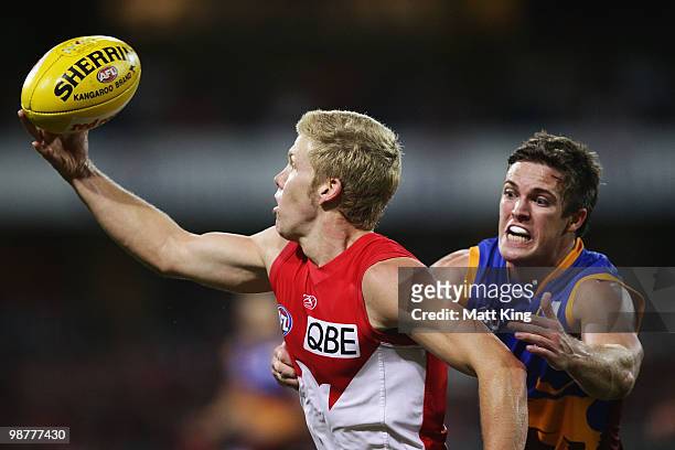 Daniel Hannebery of the Swans juggles the ball in front of Matt Austin of the Lions during the round six AFL match between the Sydney Swans and the...