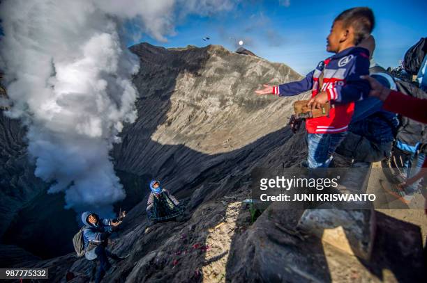 Tengger tribe boy throws small change into the crater of Bromo volcano as an offering in Probolinggo, East Java province, on June 30 as part of...