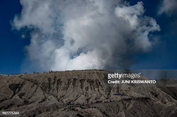 Tengger tribe people and tourists climb the summit of Bromo volcano, to throw offerings into the crater in Probolinggo, East Java province on June 30...