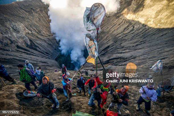 Some people prepare to catch offerings thrown by Tengger tribe people into the crater of Bromo volcano to in Probolinggo, East Java province, on June...