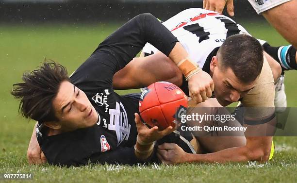 Zac Fisher of the Blues handballs whilst being tackled by Tom Rockliff of the Power during the round 15 AFL match between the Carlton Blues and the...