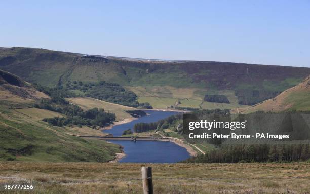 Dovestone Reservoir on Saddleworth Moor, with smoke from a fire on the hill behind, as water companies have asked customers to conserve supplies by...