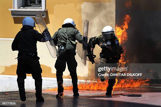 Greek riot policeman runs away from a fire after a group set fire with a molotov cocktail, during a May day demonstration in Athens on May 1, 2010....
