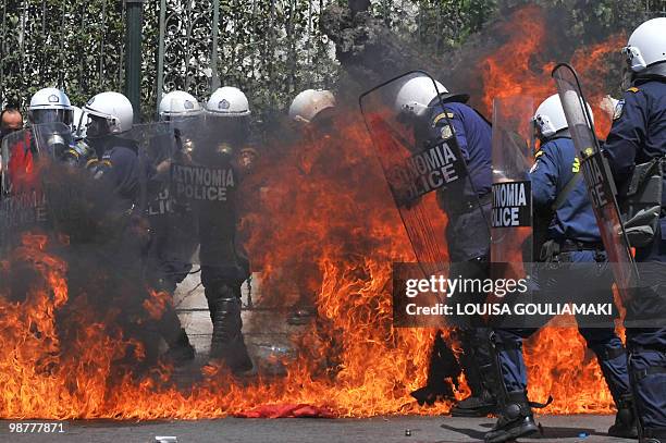 Policemen use their shields to protect themselves after a fire was set up with molotov cocktail, outside the greek Parliament during a Mayday...