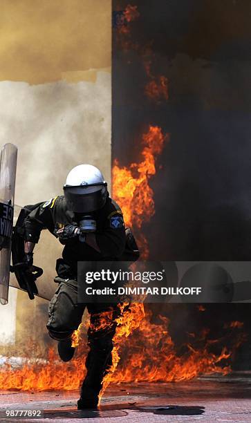 Greek riot policeman runs away from a fire after a group set fire with a molotov cocktail, during a May day demonstration in Athens on May 1, 2010....