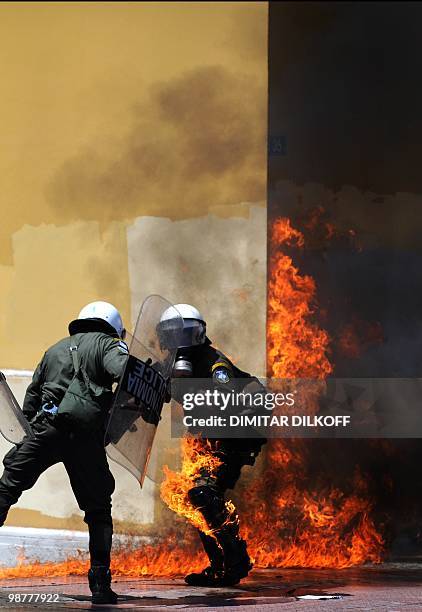 Greek riot policemen run away from a fire after a group set fire with a molotov cocktail, during a May day demonstration in Athens on May 1, 2010....