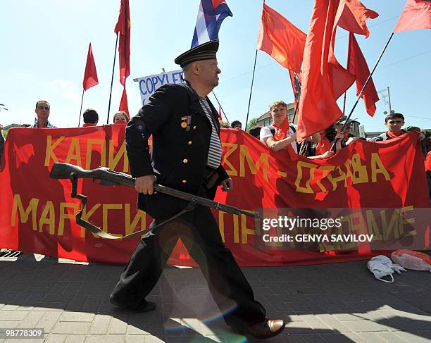 Man dressed as "Revolution" sailorman walks in front of the banner of far left activists during a rally to mark May Day in Kiev�s downtown on May 1,...