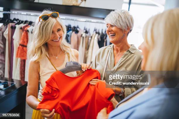 fashionable mature women shopping for clothes in fashion boutique - 60s fashion woman stock pictures, royalty-free photos & images