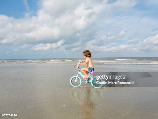 4 year  old boy riding hs bike at the beach - marc romanelli stock pictures, royalty-free photos & images
