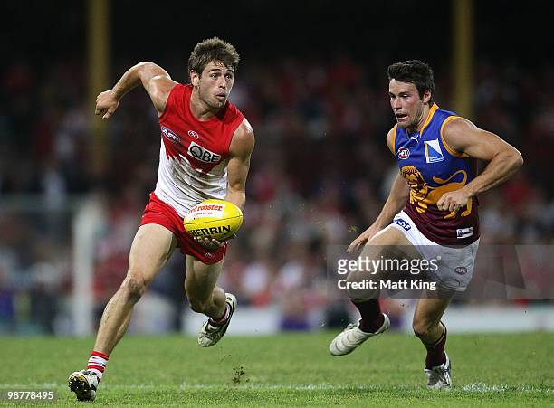 Nick Smith of the Swans handballs under pressure from Andrew Raines of the Lions during the round six AFL match between the Sydney Swans and the...