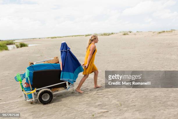 young girl pulling beach cart - marc romanelli stock pictures, royalty-free photos & images
