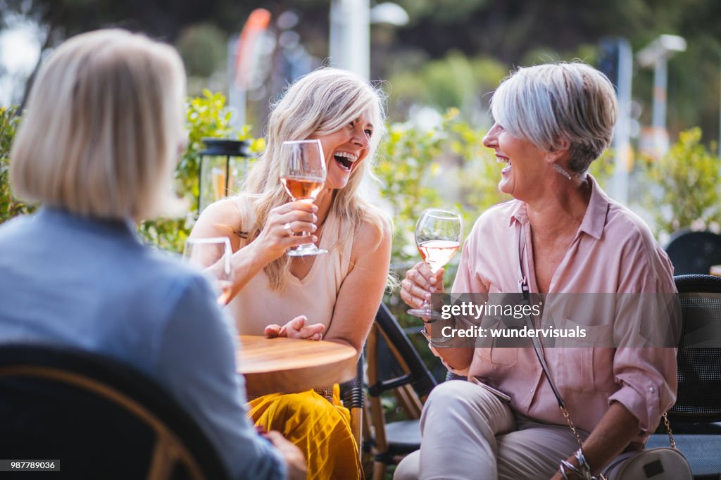 Felizes mulheres sênior, bebendo vinho e rindo juntos no restaurante