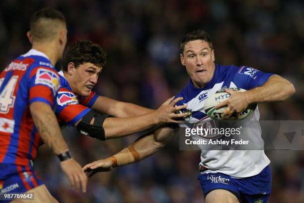 Josh Jackson of the Bulldogs is tackled by the Knights defence during the round 16 NRL match between the Newcastle Knights and the Canterbury...