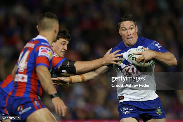 Josh Jackson of the Bulldogs is tackled by the Knights defence during the round 16 NRL match between the Newcastle Knights and the Canterbury...