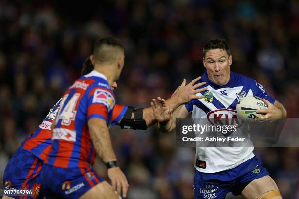 Josh Jackson of the Bulldogs is tackled by the Knights defence during the round 16 NRL match between the Newcastle Knights and the Canterbury...