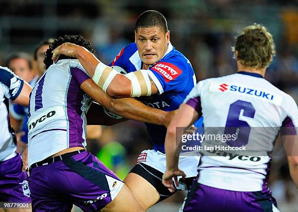 Willie Mason of the Cowboys looks to get through Adam Blair and Brett Finch of the Storm defence during the round eight NRL match between the North...