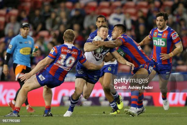 Brett Morris of the Bulldogs is tackled by the Knights defence during the round 16 NRL match between the Newcastle Knights and the Canterbury...