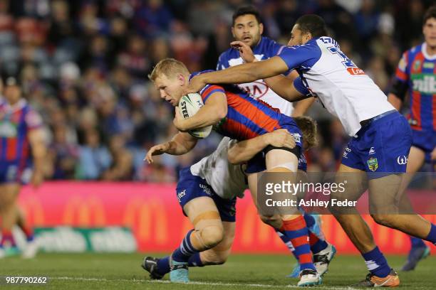 Slade Griffin of the Knights is tackled by the Bulldogs defence during the round 16 NRL match between the Newcastle Knights and the Canterbury...