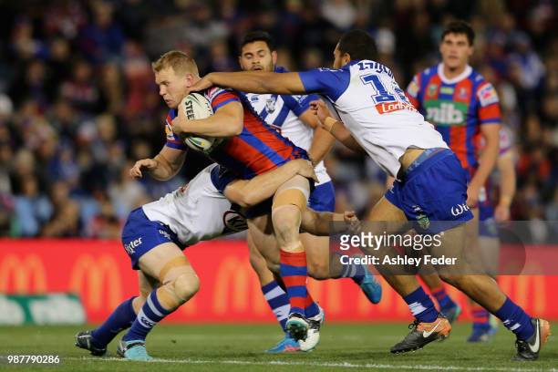 Slade Griffin of the Knights is tackled by the Bulldogs defence during the round 16 NRL match between the Newcastle Knights and the Canterbury...