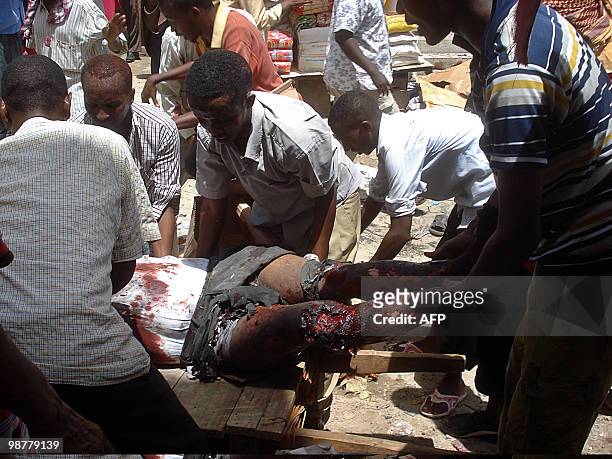 Men evacuate a man wounded on May 1, 2010 near Bakara market, after two explosions rocked a mosque in a crowded area of Somalia's restive capital...