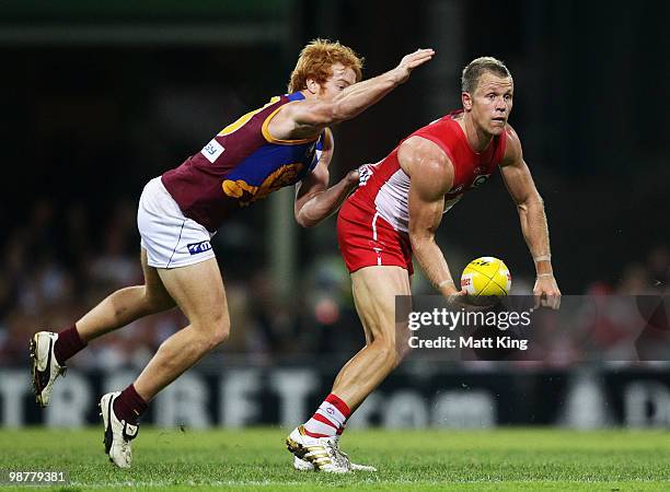 Ryan O'Keefe of the Swans handballs under pressure from Matt Austin of the Lions during the round six AFL match between the Sydney Swans and the...