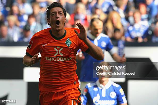 Mesut Oezil of Bremen celebrates the first goal and Benedikt Hoewedes of Schalke looks dejected during the Bundesliga match between FC Schalke 04 and...