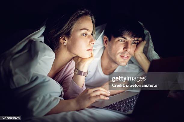 mobiele telefoon verslaving - paar is texting en browsen in het bed - addiction mobile and laptop stockfoto's en -beelden