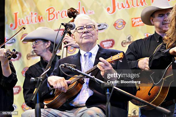 Warren Buffett, chief executive officer of Berkshire Hathaway, plays the ukulele during a tour of the exhibition floor prior to the Berkshire...