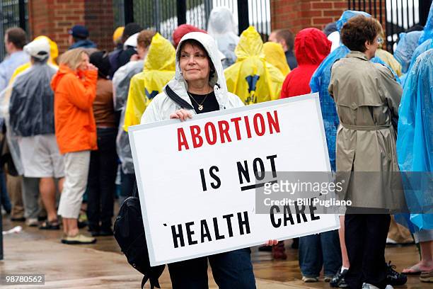 Protestor holds up an anti abortion sign outside the University of Michigan Stadium as people line up to get in to hear U.S. President Barack Obama's...