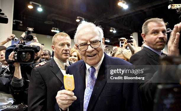 Warren Buffett, chief executive officer of Berkshire Hathaway, eats a Dairy Queen vanilla orange ice-cream bar as he tours the exhibition floor prior...