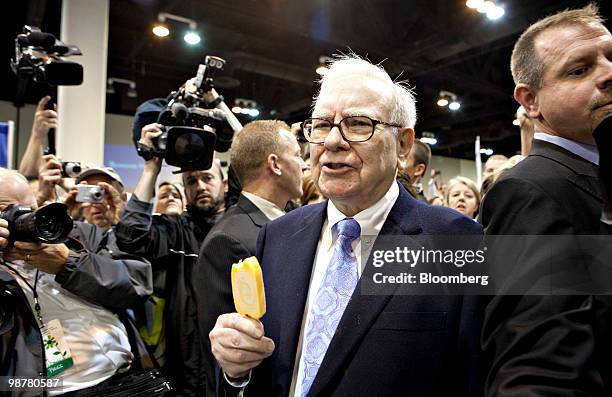 Warren Buffett, chief executive officer of Berkshire Hathaway, eats a Dairy Queen vanilla orange ice-cream bar as he tours the exhibition floor prior...