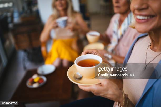 amigas maduras disfrutando de una taza de té en el café - tea fotografías e imágenes de stock