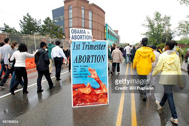 Protestor holds up an anti abortion sign outside the University of Michigan Stadium as people line up to get in to hear U.S. President Barack Obama's...