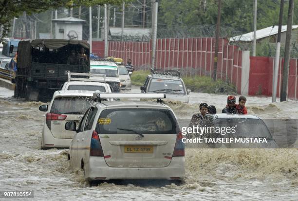 Vehicles drive along a flooded road after a heavy rainfall in Srinagar on June 30, 2018. - Authorities issued a flood alert in central Kashmir for...
