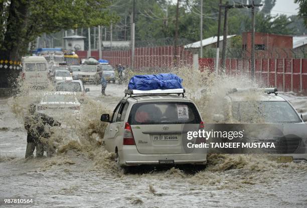 Vehicles drive along a flooded road after a heavy rainfall in Srinagar on June 30, 2018. - Authorities issued a flood alert in central Kashmir for...