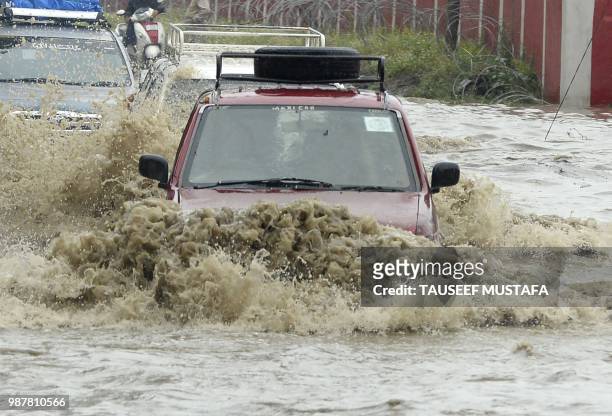 Vehicles drive along a flooded road after a heavy rainfall in Srinagar on June 30, 2018. - Authorities issued a flood alert in central Kashmir for...