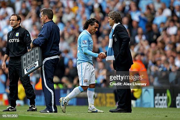 Carlos Tevez of Manchester City shakes hands with his manager, Roberto Mancini as he leaves the pitch after being substituted in the second half...