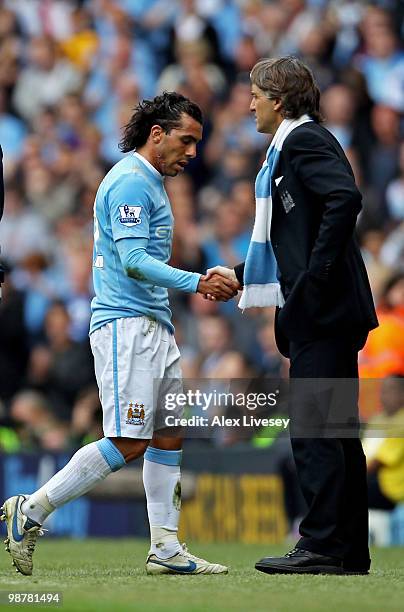 Carlos Tevez of Manchester City shakes hands with his manager, Roberto Mancini as he leaves the pitch after being substituted in the second half...