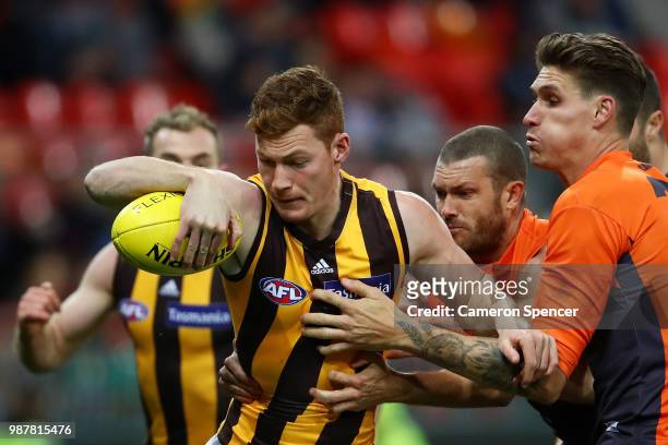 Tim O'Brien of the Hawks is tackled during the round 15 AFL match between the Greater Western Sydney Giants and the Hawthorn Hawks at Spotless...
