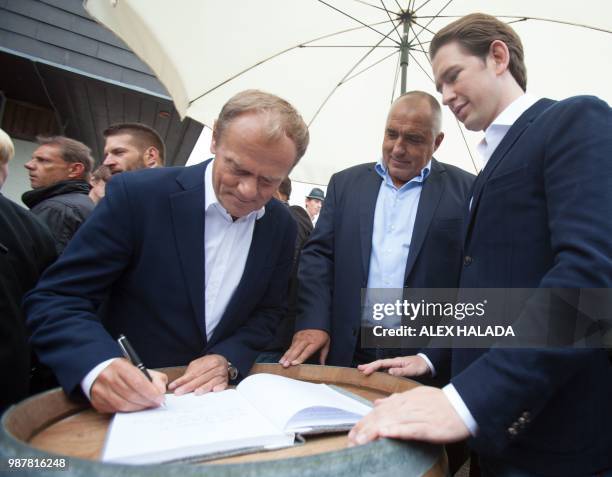 President of the European Council Donald Tusk signs the mountain Planai summit book in front of the cable car station next to Austrian Chancellor...